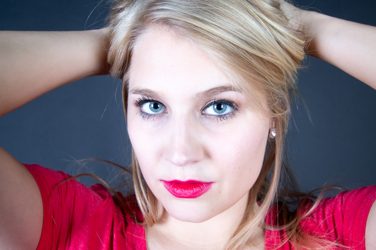Professional headshot of woman with blue eyes wearing red against dark backdrop