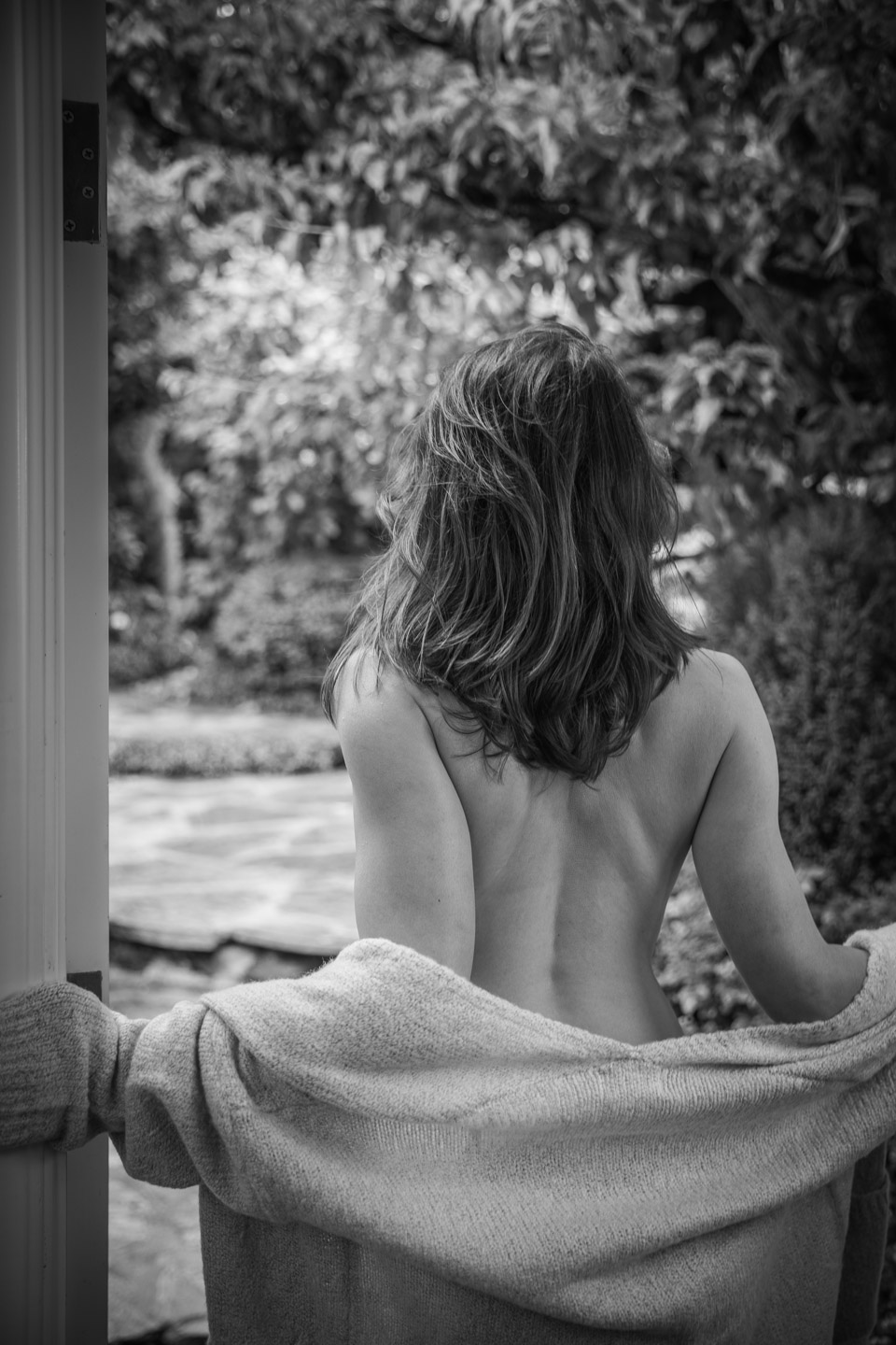Woman from behind gazing at garden, artistic black and white portrait